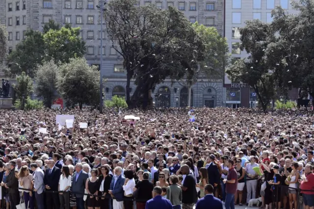 People wait before a minute of silence for the victims of the Barcelona attack at Plaza de Catalunya