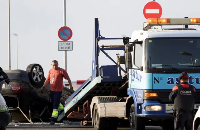 A worker loads a car on a tow truck where the police investigate the scene of an attack in Cambrils