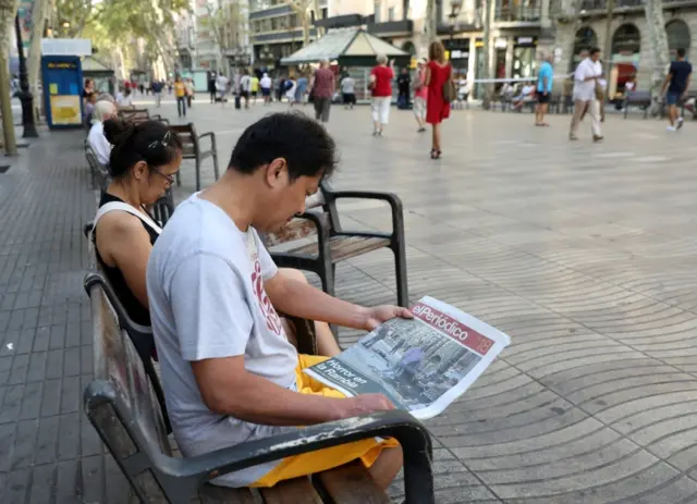 A man sits on a bench as he reads a newspaper at Las Ramblas