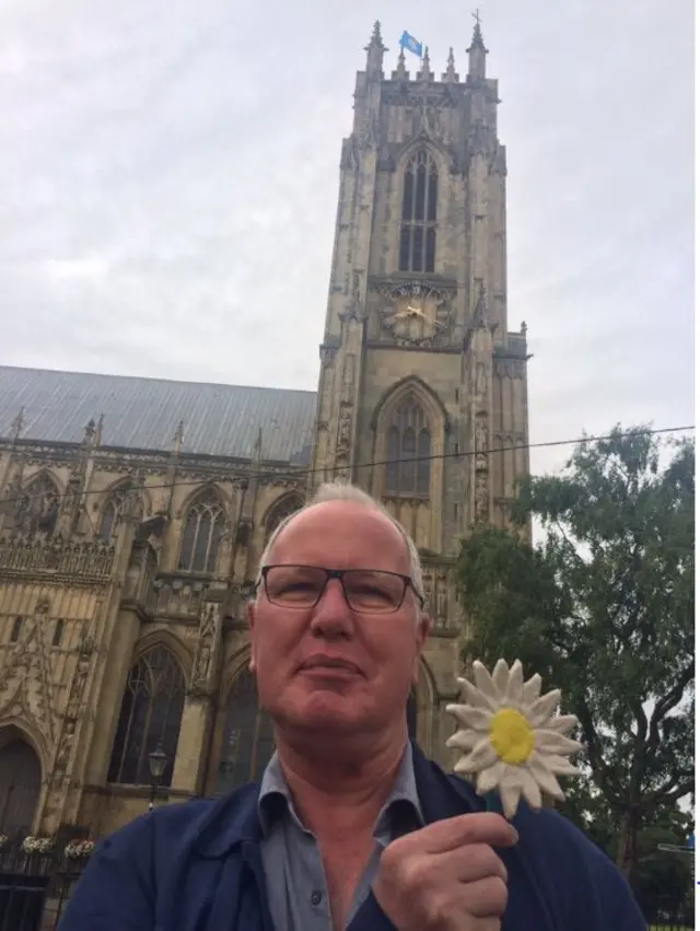 Man holding a large white ceramic daisy