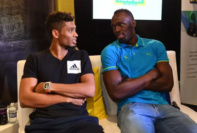 Usain Bolt of Jamaica (R) chats with Wayde Van Niekerk of South Africa