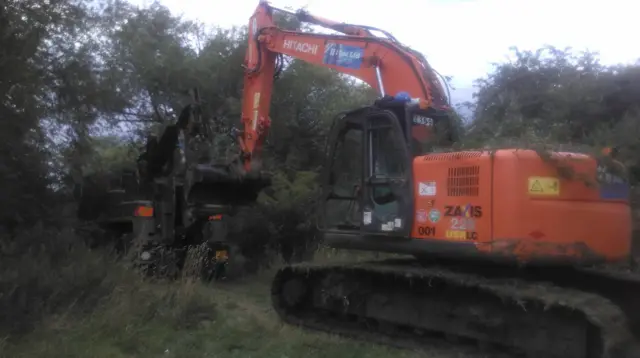 Digger is pulled from the water by recovery vehicles