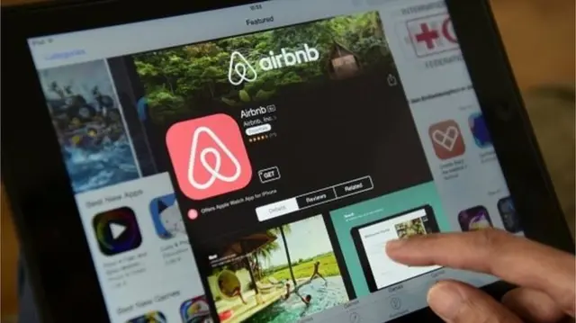 A person scrolls through the airbnb app on an iPad