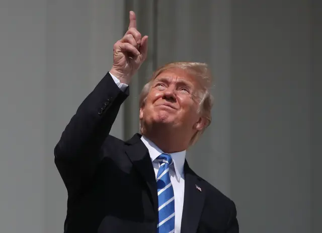 Donald Trump  points to the eclipse without wearing glasses