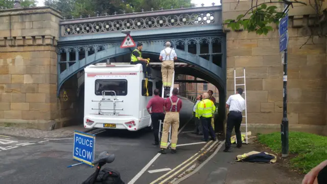 Camper van stuck under bridge