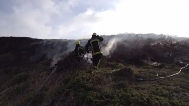 Firemen dampen down the fire on Sark's cliffs