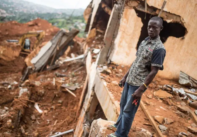 Man standing by destroyed house