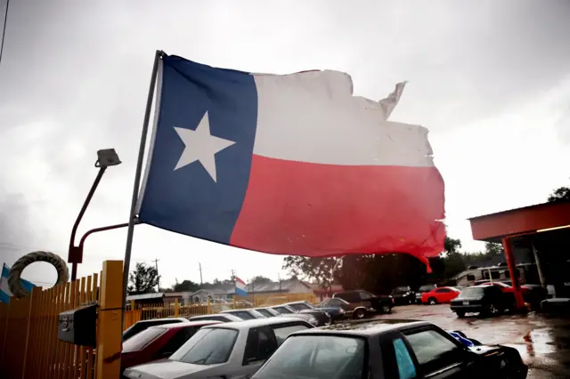 Wind from Hurricane Harvey batters a Texas flag on August 26, 2017 in Houston, Texas