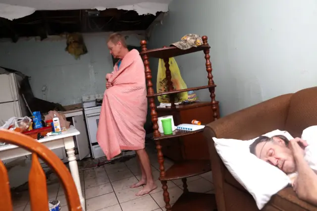 Terry Smith stands in the kitchen as Henry McKay sleeps in the apartment where the ceiling collapse when Hurricane Harvey hit on August 26, 2017 in Rockport, Texas.