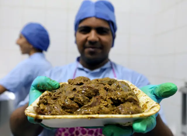 An employee dressed as a doctor holds a plate of spiced up beef liver at in the operating room-themed fast food restaurant in Damanhour