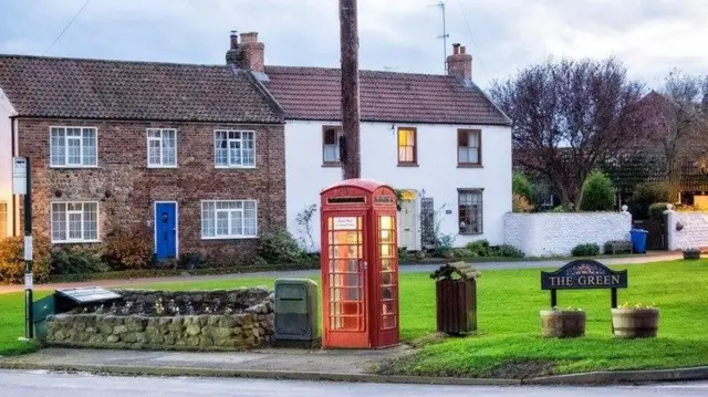 The new red phone box in the village square.