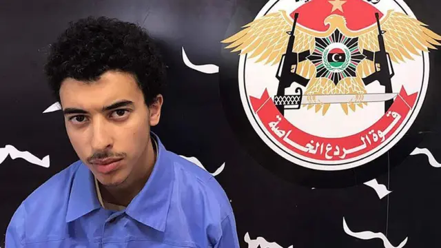 Hashem Abedi is seen next to the logo of Libya's Special Deterrence Forces in a handout photo dated May 25