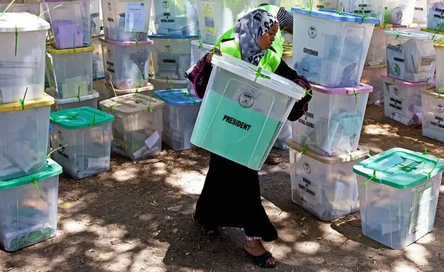 A woman handles ballot paper boxes