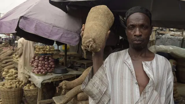 A man holds a yam at a market in Nigeria.