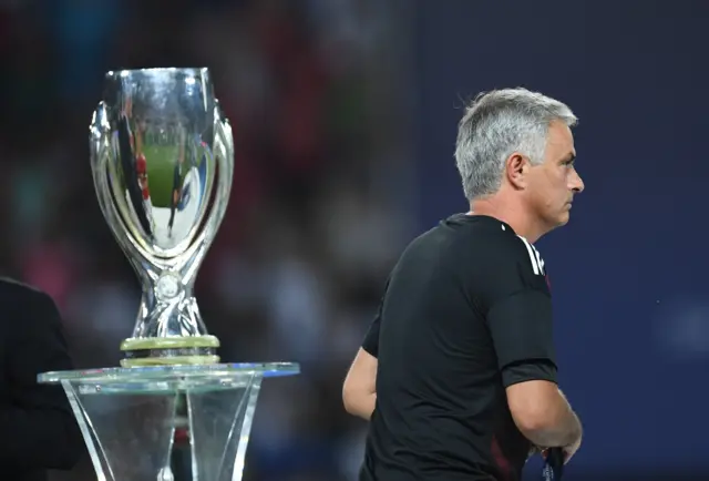 Mourinho walks past the trophy