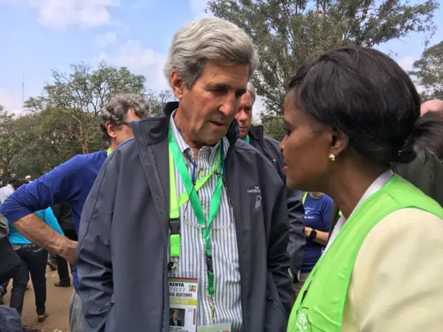 John Kerry, wearing observer identification, speaking to voting staff at a Nairobi polling booth.