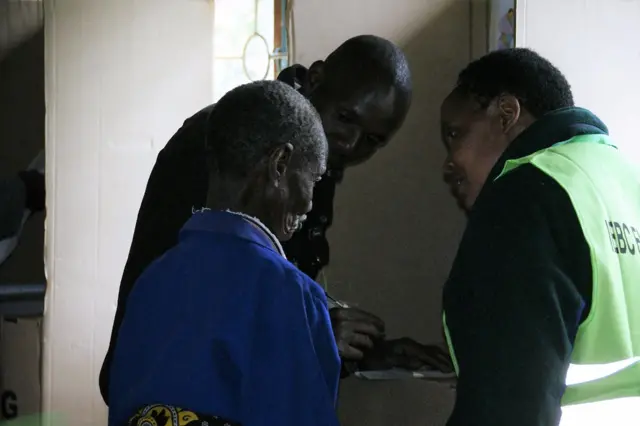 A senior citizen being helped to vote by an IEBC official at Kosachei polling station