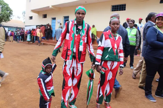 A family are dressed in suits with the Kenyan flag, with matching accessories and even hair.