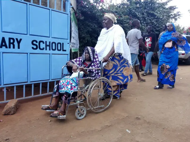 an elderly woman in a wheelchair is pushed by her daughter