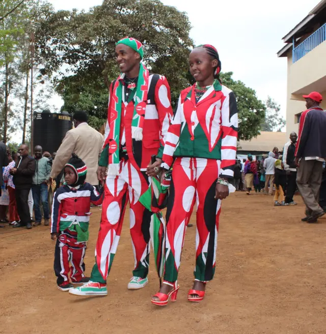 A family are dressed in suits with the Kenyan flag, with matching accessories and even hair.