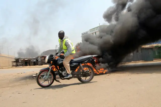 A motorcycle rider drives past tyres set on fire by demonstrators supporting opposition leader Raila Odinga, after their political leader claimed "massive" fraud in this week"s elections, in Kisumu, Kenya August 9, 2017