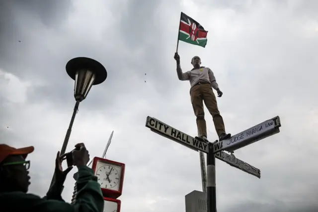 A supporter of The National Super Alliance (NASA) opposition coalition and its presidential candidate Raila Odinga stands on top of a street sign post that has been relabeled "Judge Maraga Lane", referring to Chief Justice David Maraga, and "Orengo Street", referring to NASA"s lawyer James Orengo, in front of the Supreme Court in central Nairobi, Kenya, 01 September 2017. K