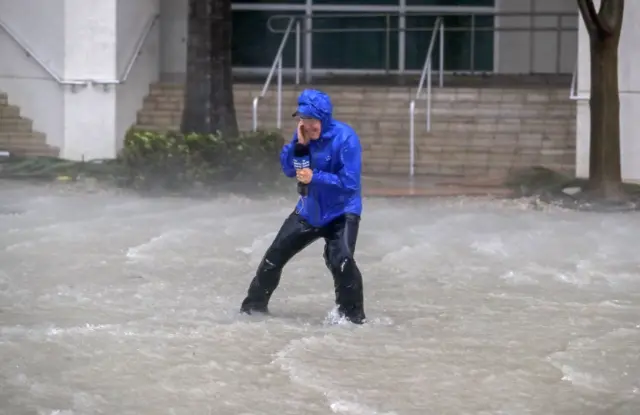 Presenter on the weather channel faces strong winds and is shin-deep in flooding water in Miami