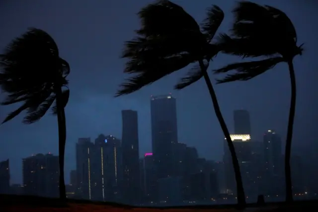 Gloomy image of storm coming in to Miami skyline, with much of it in darkness