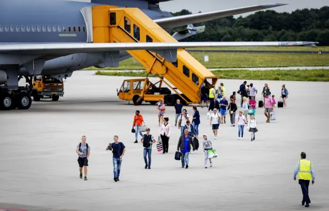 Tourists pictured on the tarmac walking away from a plane