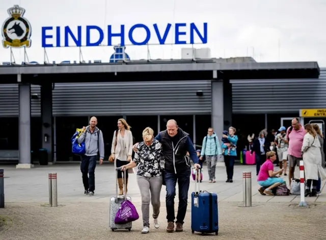 A couple with bags are pictured leaving the military airport