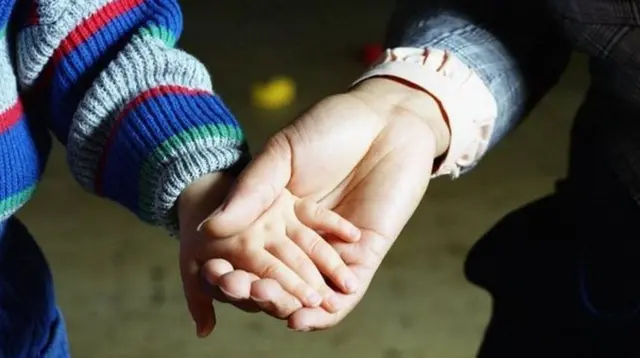 Adult and child holding hands - generic image