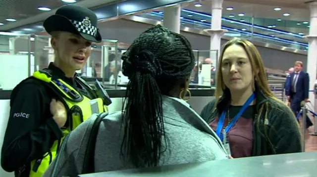 A police officer and a border official speaking to a woman