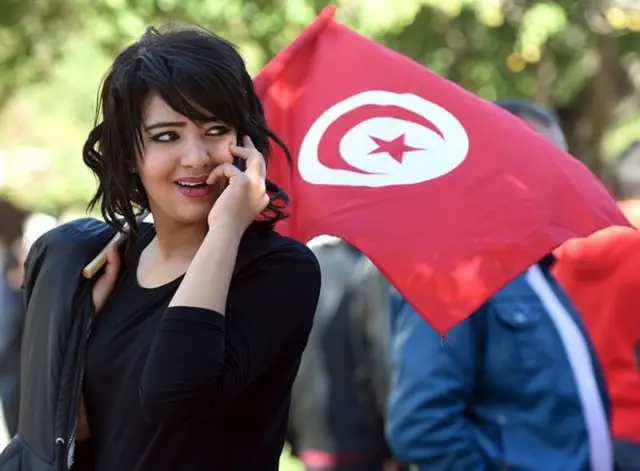 A Tunisian women holds the national flag