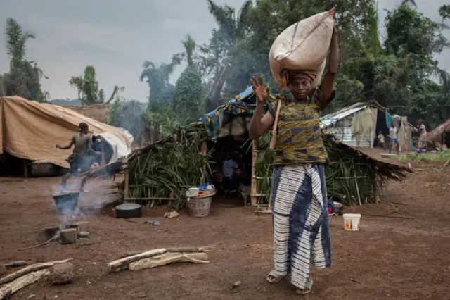 A woman waves at the camera in a refugee camp in DR Congo