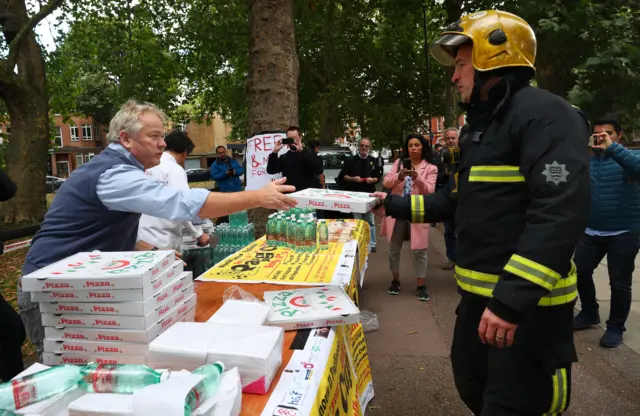 Staff from a local Italian restaurant hands out pizza and water from a stall near Parsons Green tube station