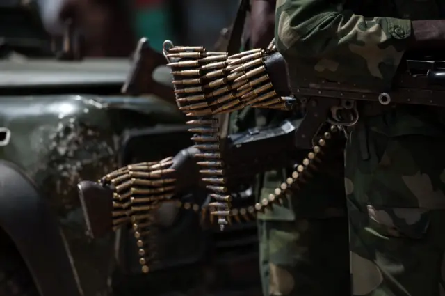 A chain of bullets hang from the butt of a rifle of a Congolese National Army soldier