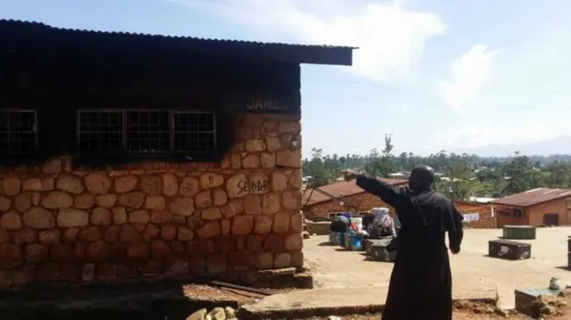 A man points to the fire damage to the school building