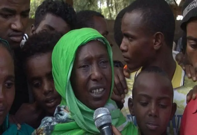 A crying woman speaks to a reporter