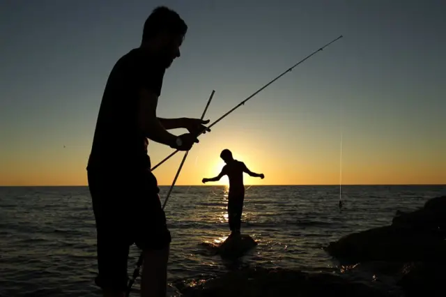 Libyan men fish off the coast