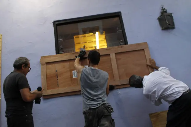 Image shows people in San Juan, Puerto Rico, boarding up windows in preparation for Hurricane Maria on 19 September