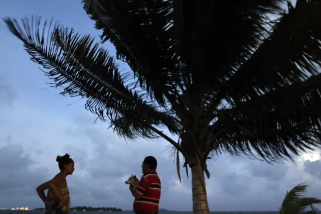 A couple watch the sunset from a seafront as Hurricane Irma approaches Puerto Rico in Fajardo on September 5, 2017