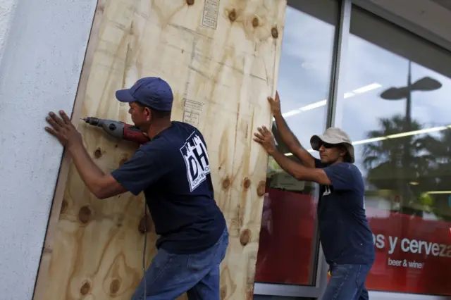 People board up windows of a business in preparation for the anticipated arrival of Hurricane Maria in San Juan, Puerto Rico