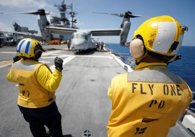 Crewmen direct pilots aboard a MV-22B Osprey on the deck of the USS Kearsarge