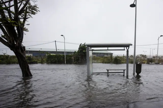 Image shows a flooded road and a bus stop on 19 September 2017 in the French territory of Guadeloupe after the passage of Hurricane Maria