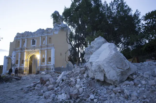 The church is shown severely damaged with no roof, surrounded by rubble