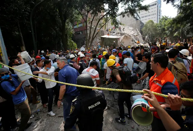 People carry buckets to help remove the rubble of a collapsed building after an earthquake hit Mexico City, Mexico, 19 September 2017