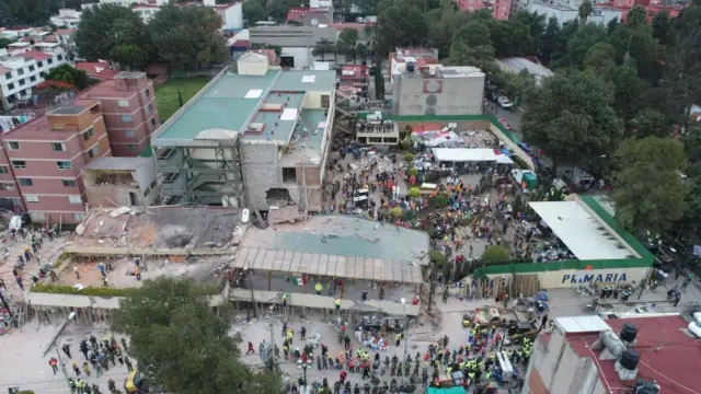 Image shows the collapsed school in Mexico City surrounded by rescue workers