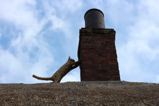 a straw cat climbs the chimney