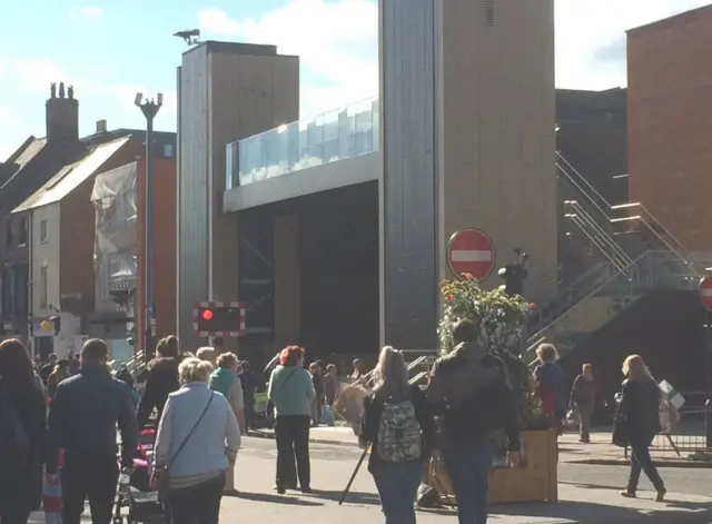 People wait at the level crossing at the foot of the footbridge.