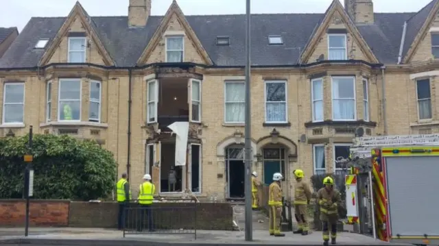 Fire fighters outside the building with its windows blown out.